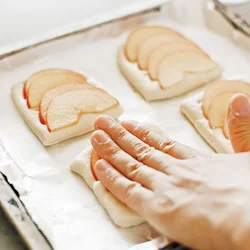 焼成時にりんごが落ちるのを防ぐため、上から押して生地にくっつけてから、調味料をのせる。