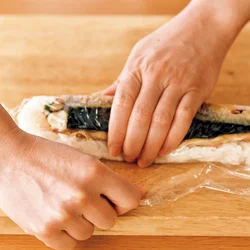 両端はラップを折り返し、さばからはみ出したすし飯を押し込みながら形を整えます。