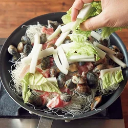 ビーフンはもどさず、火をつける前のフライパンへ。豚肉、あさり、白菜など好みの具をたっぷりのせる。