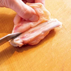 皮を上にして置き、皮の部分を持ち上げて肉を開くようにそぎ、2本あるうちの細いほうの骨の先に切り込みを入れる。