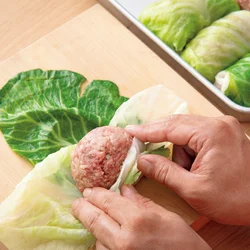 大きい葉に小さい葉2～3枚を手前に左右に広げて重ね、肉だねをのせる。手前、左右の順にきつく折り、向こう側へくるりときつく巻く。フライパンにギュウギュウに詰めるので、ようじで留める必要はない。