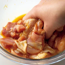 とり肉に卵や調味料をもみ込む